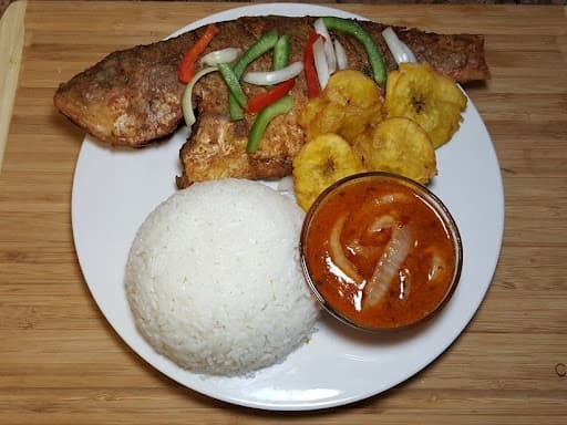 Whole fried red snapper plated with rice and pikliz